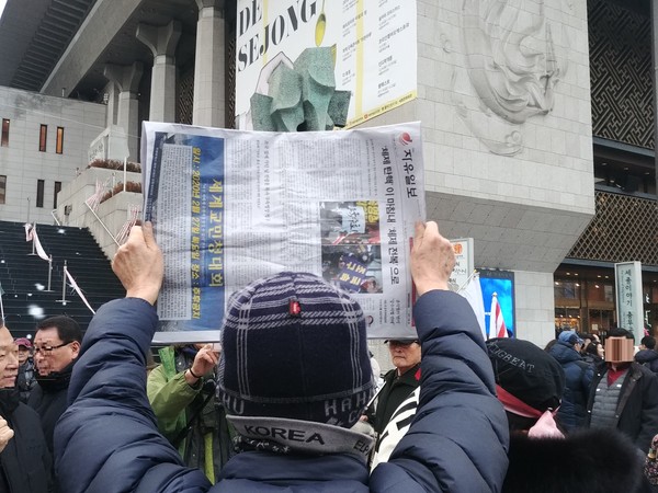 거리 가판대에서 자유일보를 들어보이는 서명대 봉사자(사진=평화나무 박종찬, 2019.12.28.)